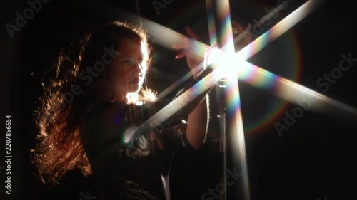 Woman in a metallic dress under a huge shining star. Golden rays and rainbow halo on black, wide frame with free space for festive greetings.