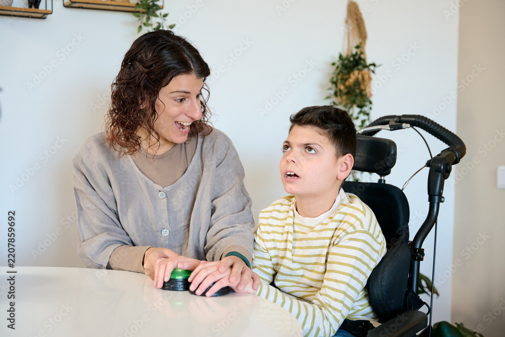 Fototapeta premium Therapist assisting boy with cerebral palsy using communication device
