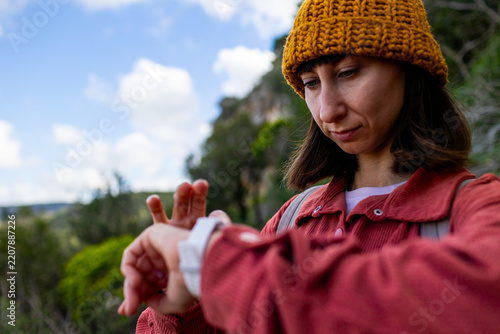 A young woman looks at her smartwatch. Checking her smartwatch. A woman in the forest uses a smartwatch as a navigation device during a hike.