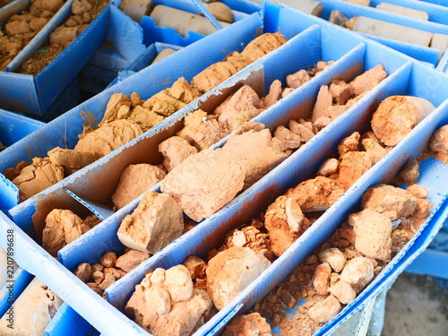 Close up of weathered clay and stone drill core samples in blue plastic storage boxes