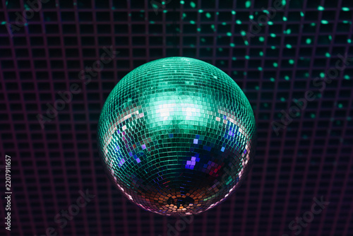 disco ball with mirror surface and bright rays, green light, hanging on ceiling, night party background