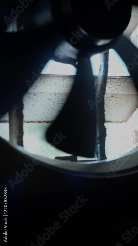 Front-facing close-up of industrial axial fan hub with silhouetted curved blades in tight symmetrical composition, vertical