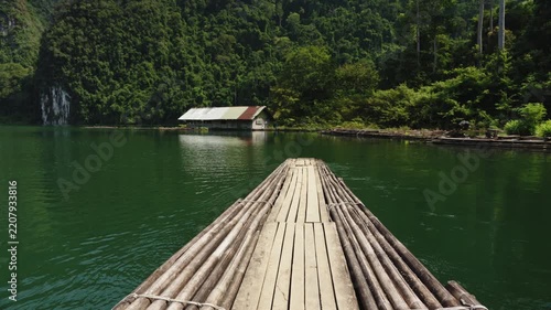 Cinematic POV of a Traditional Bamboo Raft Navigating Across Emerald Waters Toward Dense Tropical Rainforest, Cheow Lan Lake, Khao Sok