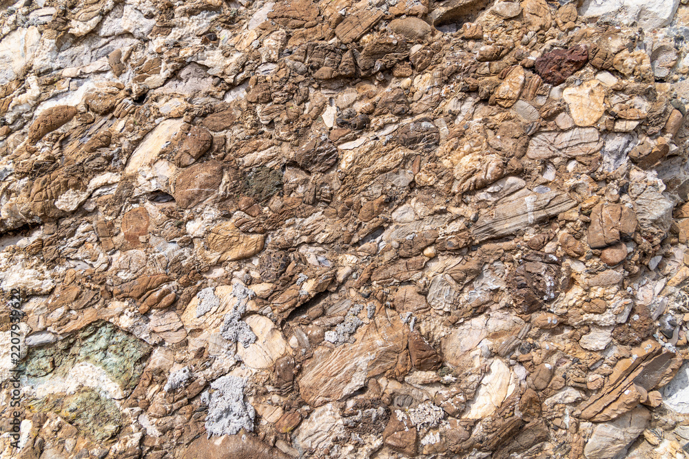 Obraz premium Rough brown conglomerate rock surface with mixed stone fragments