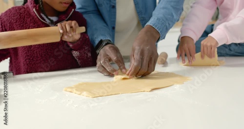 African family father guiding two children rolling dough for christmas at kitchen with wooden pin