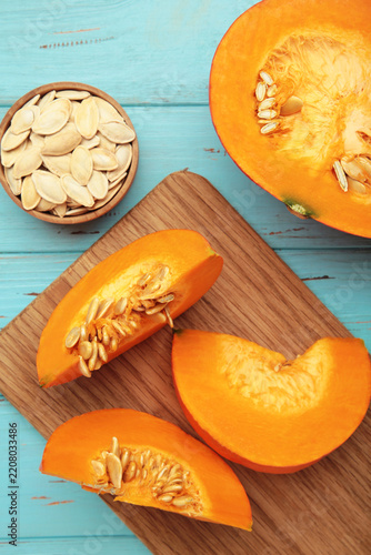 Sliced Hokkaido pumpkin with seeds on bowl on blue wooden background. Vertical photo