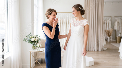 Proud mother reacting to daughter trying on her wedding dress