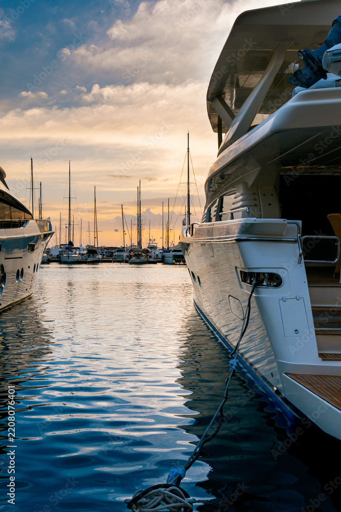 Fototapeta premium Vertical view of modern luxury motor yacht stern moored at a marina pier