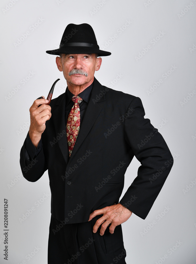 Naklejka premium Porträtserie eines älteren Mannes im Anzug und Hut mit Pfeife – einmal frontal, einmal als Silhouette. Charakterporträt, Noir-Stil, Geheimnis, Retro-Look und inszenierte Studiofotografie
