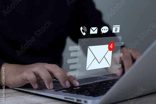 Customer contact us and email marketing concept with user hands typing on laptop keyboard displaying virtual envelope with email notification badge and communication channels.