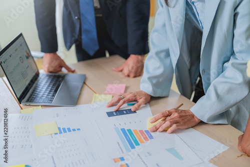 overhead shot of a business team's hands pointing at financial charts on a tablet, surrounded by printed reports and sticky notes. This detailed scene captures collaborative data analysis and strategi
