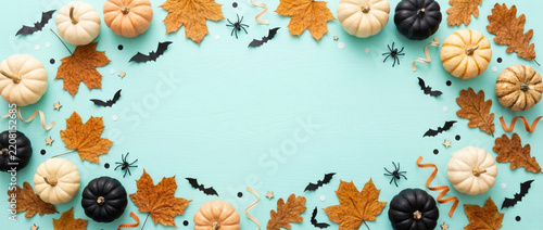 Halloween flat lay: pumpkins, bats, autumn leaves on aqua background