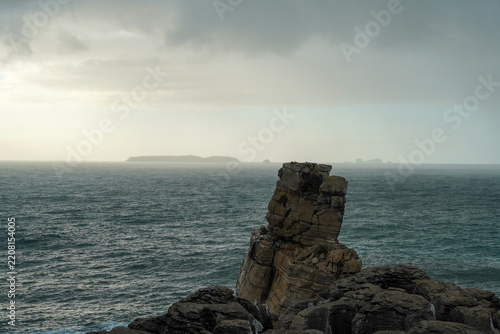 Dramatic view of Nau dos Corvos sea stack at Cabo Carvoeiro in Peniche, Portugal, under a stormy sky
