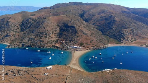 Aerial view of the double-sided beach connecting two hills with boats anchored in the blue sea in Islands, Greece.