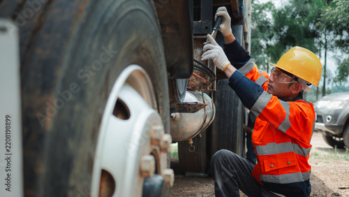 Male Mechanic Inspecting Commercial Truck Wheel Suspension Maintenance