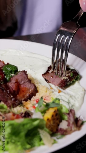 Vertical video of a fork dipping sliced steak into sauce