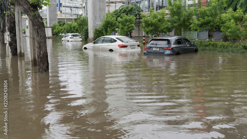 Cars submerged in deep flood water on a city street after heavy rainfall and urban storm damage