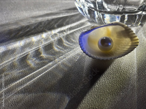 Seashell with pearl surrounded by glass reflections and colorful light refractions