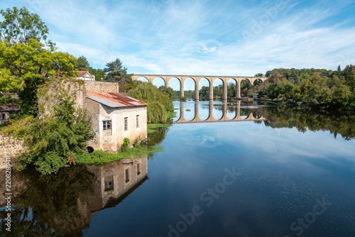 old railway viaduct over the river Vienne at L'Isle Jourdain in France built in 1884 reflecting in the water