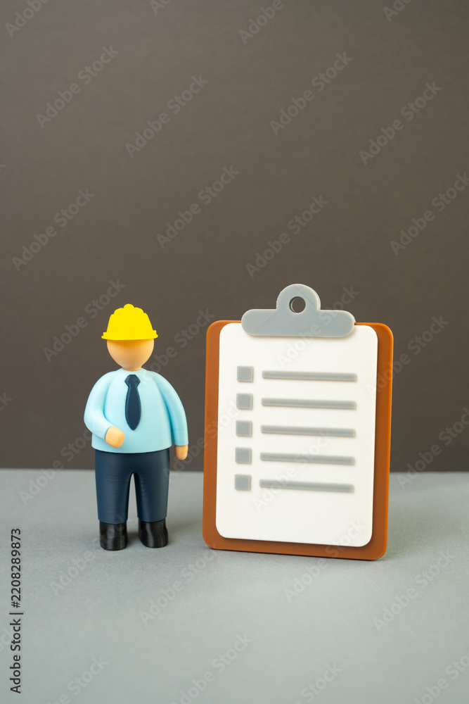 Fototapeta premium Official in a yellow hard hat with a paper clipboard. Inspections and tests. Audits and occupational safety standards. Construction compliance, workplace regulations and quality control.