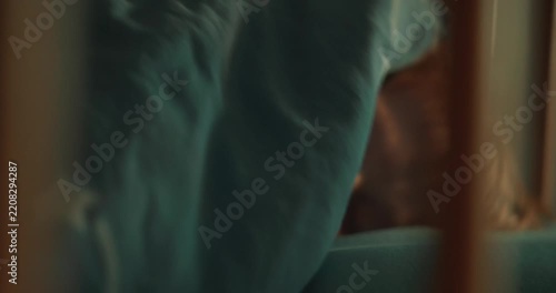 Eight-year-old boy lies comfortably in bed and looks directly at the static camera before pulling the blanket over his face and hiding underneath it in a cozy bedroom. High quality 4k footage