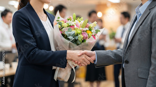 送別会で花束を受け取り笑顔で握手するビジネスパーソン