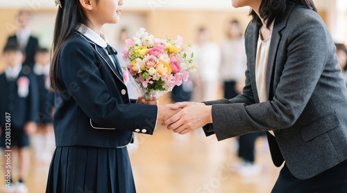 Obraz na płótnie 卒業式で花束を持ち先生と握手交わす小学生の女の子