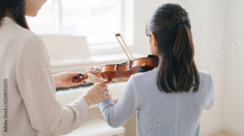 Obraz na płótnie バイオリンのレッスンを受ける女の子と指導する音楽教室の先生
