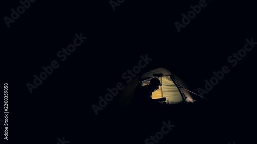 A man eating camping food inside a tent at night