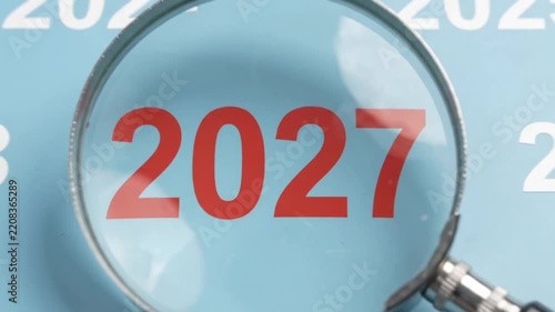Magnifying Glass Zooming In on Year 2027 Futuristic Concept with Blue Background