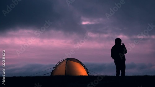 Silhouette of a man brushing his teeth while camping