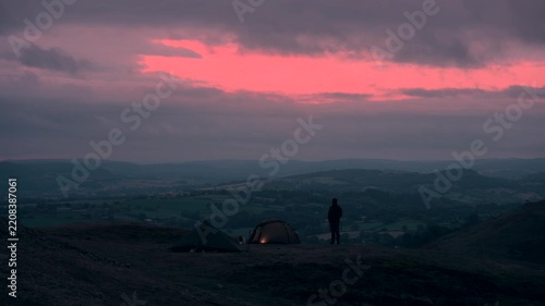 A man and two tents in the hills at dawn