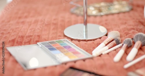 Camera is pulling focus and shifting right, revealing makeup brushes and palettes for beauty prep