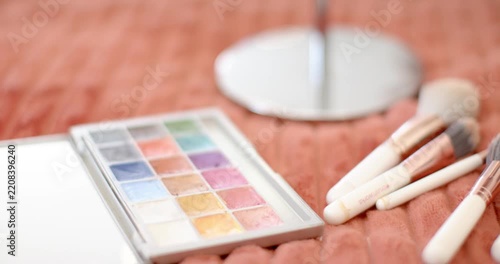 Camera is panning while hand is arranging brushes and palette for display on coral blanket