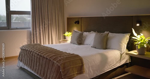 Camera is panning right and zooming, lamp is brightening to warm bed and plant in bedroom