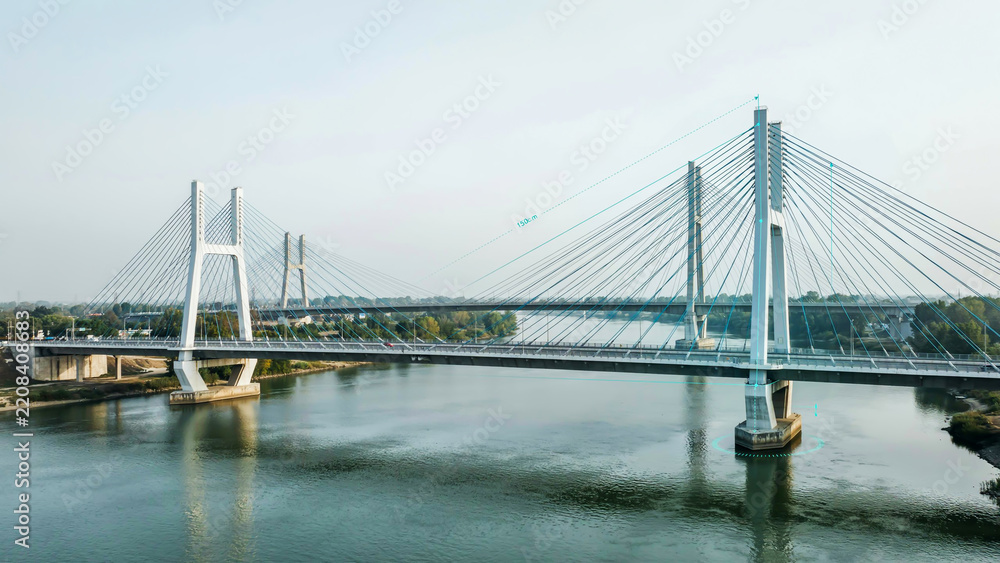 Obraz premium Modern cable-stayed bridge crossing over a calm wide river showcasing contemporary engineering design and urban infrastructure connectivity at sunset