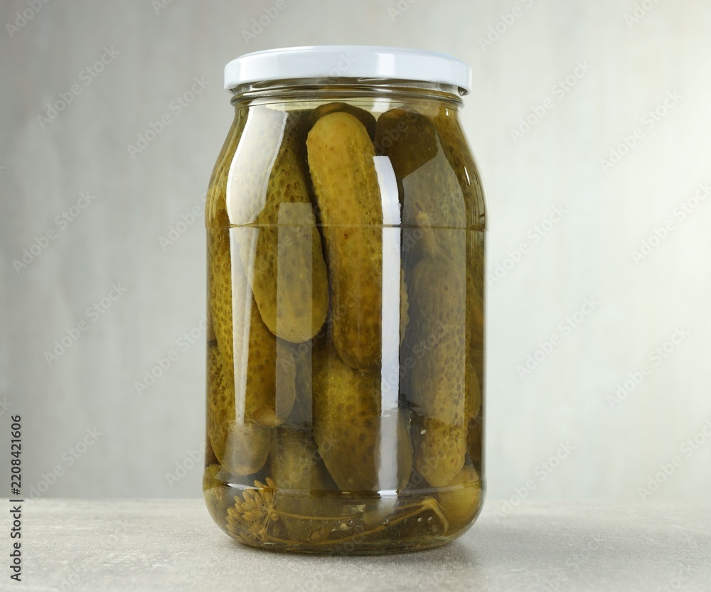 Obraz premium Pickled cucumbers in glass jar on grey table, closeup