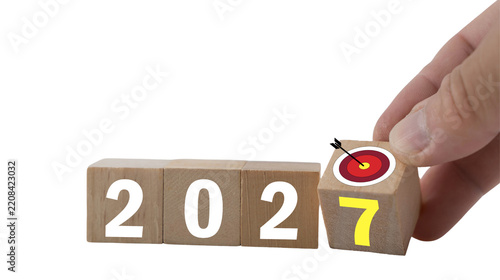 Hand placing the number seven onto 2027 wooden blocks, New Year 2027 concept, annual change, countdown, future planning and celebration with copy space