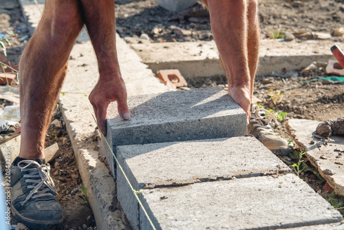 Man laying stone blocks on a construction site during daytime in a rural area