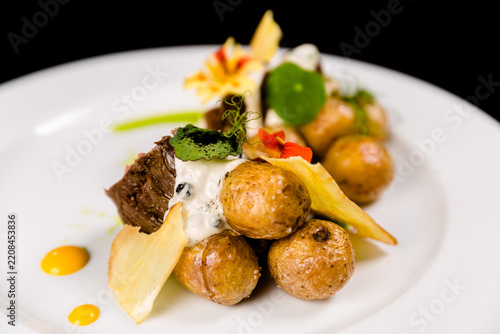 Obraz na plátně Roasted baby potatoes with beef and creamy sauce on a white plate