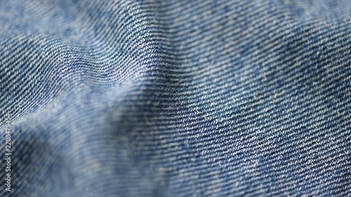 Blue denim jeans background, cotton jean fabric texture, textile backdrop, top view. Wallpaper, washed effect jean fabric close up. Rotating, slow motion 