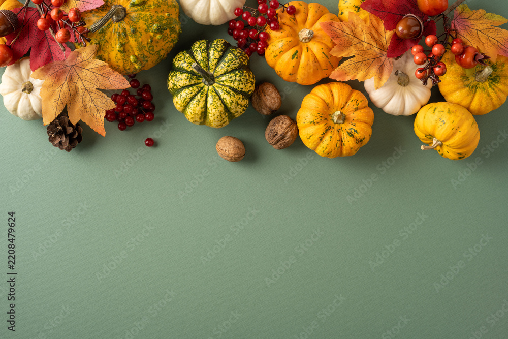 Obraz premium Autumn Thanksgiving arrangement with mini pumpkins, gourds, leaves and nuts on soft green background with empty space
