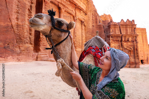 Woman Petting Camel in Front of Ancient Sandstone Temple in Petra