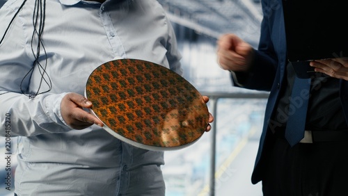 Obraz na plátně Workers in a microchip smart factory review semiconductor substrate design and photolithography while testing silicon wafer materials in production