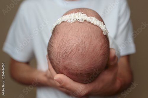 Baby with Lace Headband Held by Parent on Neutral Background