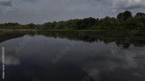 A low-altitude flight over the surface of a shallow riverbed on a cloudy, sunny summer day. Bolshaya Protoka, Novosibirsk, Russia.