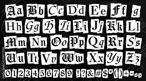 Blackletter gothic alphabet letters and numbers on torn white paper scraps against a textured black background with printed individual torn