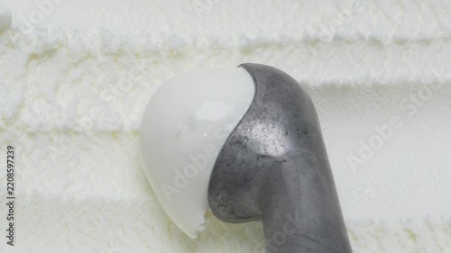 4K Metal ice cream scoop scooping rich creamy white coconut ice cream, smooth round ball for traditional Thai dessert and refreshing summer sweet treat concept.