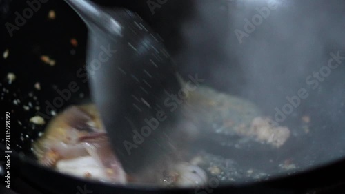 4K Chef stir-frying fresh squid rings with crushed red chilies and garlic in a hot wok, cooking process for spicy Thai stir-fried squid with holy basil concept.