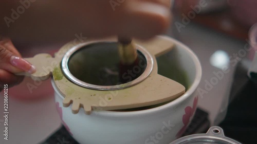 4K Sifting green tea matcha powder through fine mesh strainer into ceramic bowl, traditional preparation for Japanese matcha tea and modern cafe.